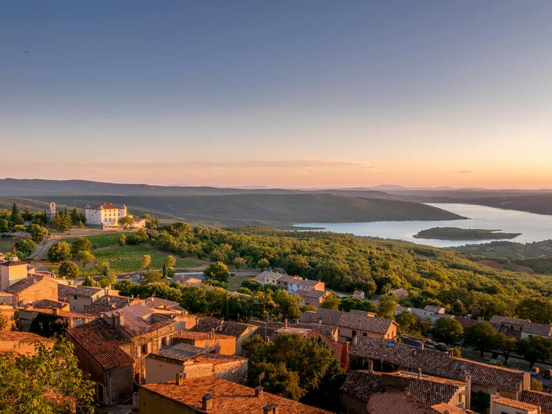 Vue panoramique au coucher de soleil sur le village d'Aiguines, avec château et lac à proxmité du camping Verdon Terra Verdon - Ciela Village à Castellane dans les Alpes-de-Haute-Provence