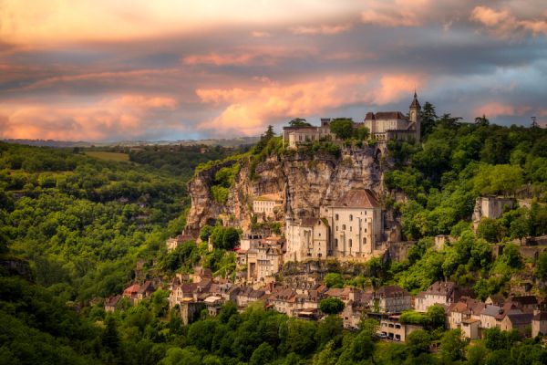 La cité médiévale de Rocamadour agrippée à sa falaise calcaire sous un ciel de coucher de soleil flamboyant dans le Lot à côté du camping Les Cigales - Ciela Village dans le Lot
