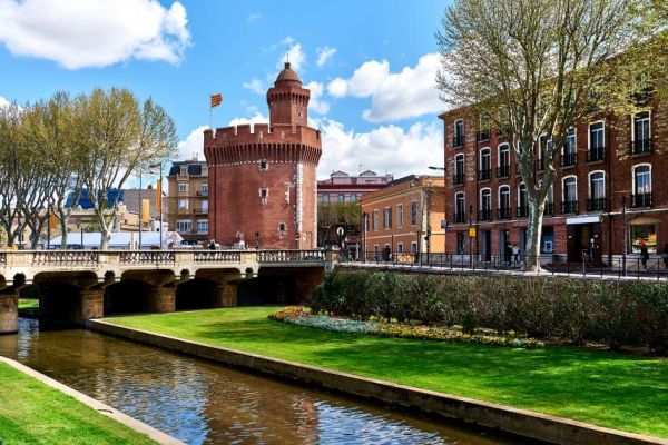 Vue sur Le Castillet, monument historique emblématique en briques rouges à Perpignan depuis les quais à proximité du camping Les Marsouins - Ciela Village à Argelès-sur-Mer en Occitanie