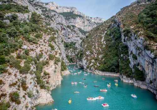 L'entrée des Gorges du lac de Sainte-Croix avec ses eaux turquoise et de nombreux pédalos naviguant entre les hautes falaises à proxmité du camping Verdon Terra Verdon - Ciela Village à Castellane dans les Alpes-de-Haute-Provence