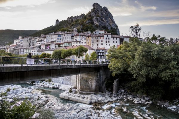 Le village médiéval de Serres niché au pied d'une immense falaise rocheuse sous un ciel bleu près Camping Les Princes d'Orange - Ciela Village à Orpierre dans les Hautes-Alpes