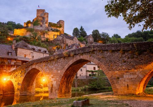 Vue panoramique sur le pont illuminé et château fort du village de Belcastel près Camping Le Caussanel - Ciela Village à Canet-de-Salars dans l'Aveyron