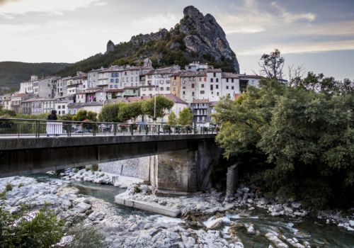 Le village médiéval de Serres niché au pied d'une immense falaise rocheuse sous un ciel bleu près Camping Les Princes d'Orange - Ciela Village à Orpierre dans les Hautes-Alpes