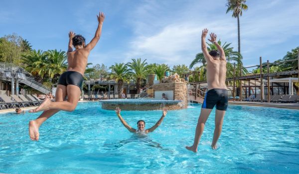 Adolescents qui sautent dans la piscine du parc aquatique du