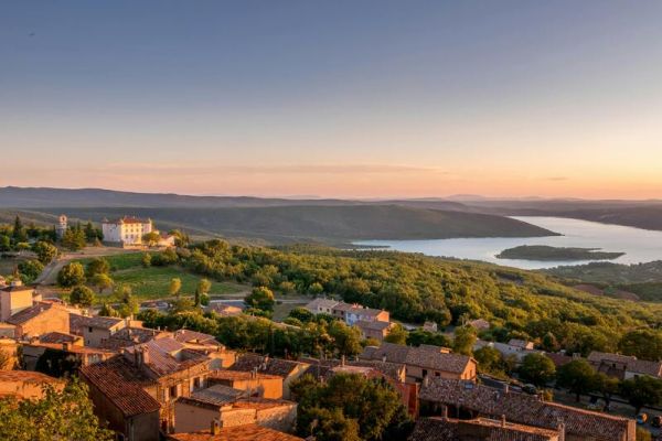 Vue panoramique au coucher de soleil sur le village d'Aiguines, avec château et lac à proxmité du camping Verdon Terra Verdon - Ciela Village à Castellane dans les Alpes-de-Haute-Provence