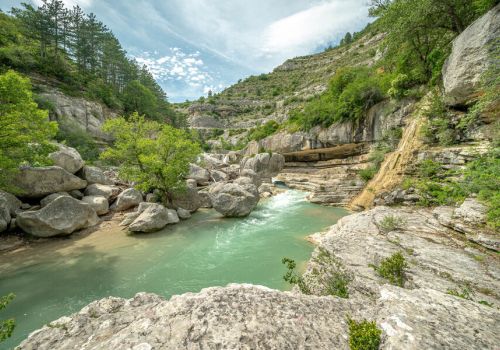 Paysage sauvage des Gorges de la Méouge avec ses vasques d'eau claire et ses falaises boisées sous un ciel voilé près du Camping Les Princes d'Orange - Ciela Village à Orpierre dans les Hautes-Alpes