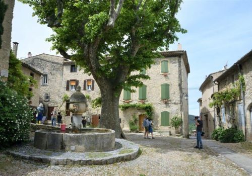 Village avec fontaine à eau, ruelle pavée et maisons en pierre dans le village d'Alba-La-Romaine à proximité du camping Le Pommier - Ciela Village à Villeneuve de Berg en Ardèche