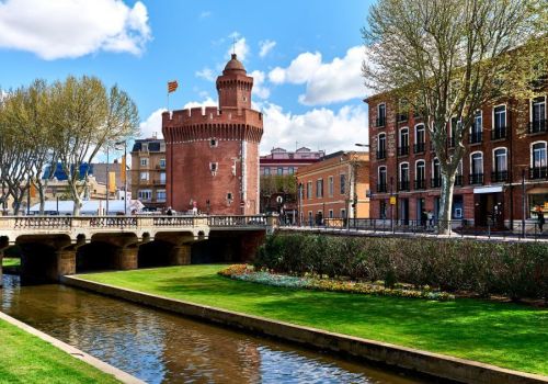 Vue sur Le Castillet, monument historique emblématique en briques rouges à Perpignan depuis les quais à proximité du camping Les Marsouins - Ciela Village à Argelès-sur-Mer en Occitanie