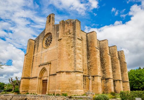Une église en vieille pierre à Loupian sou un grand ciel bleu à proximité du camping Beau Rivage - Ciela Village à Mèze dans l'Hérault